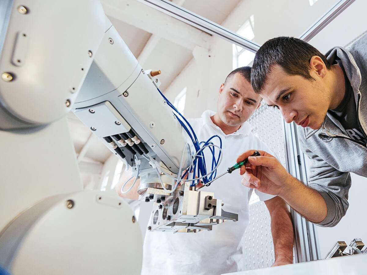 Two techs fine tuning a robotic arm